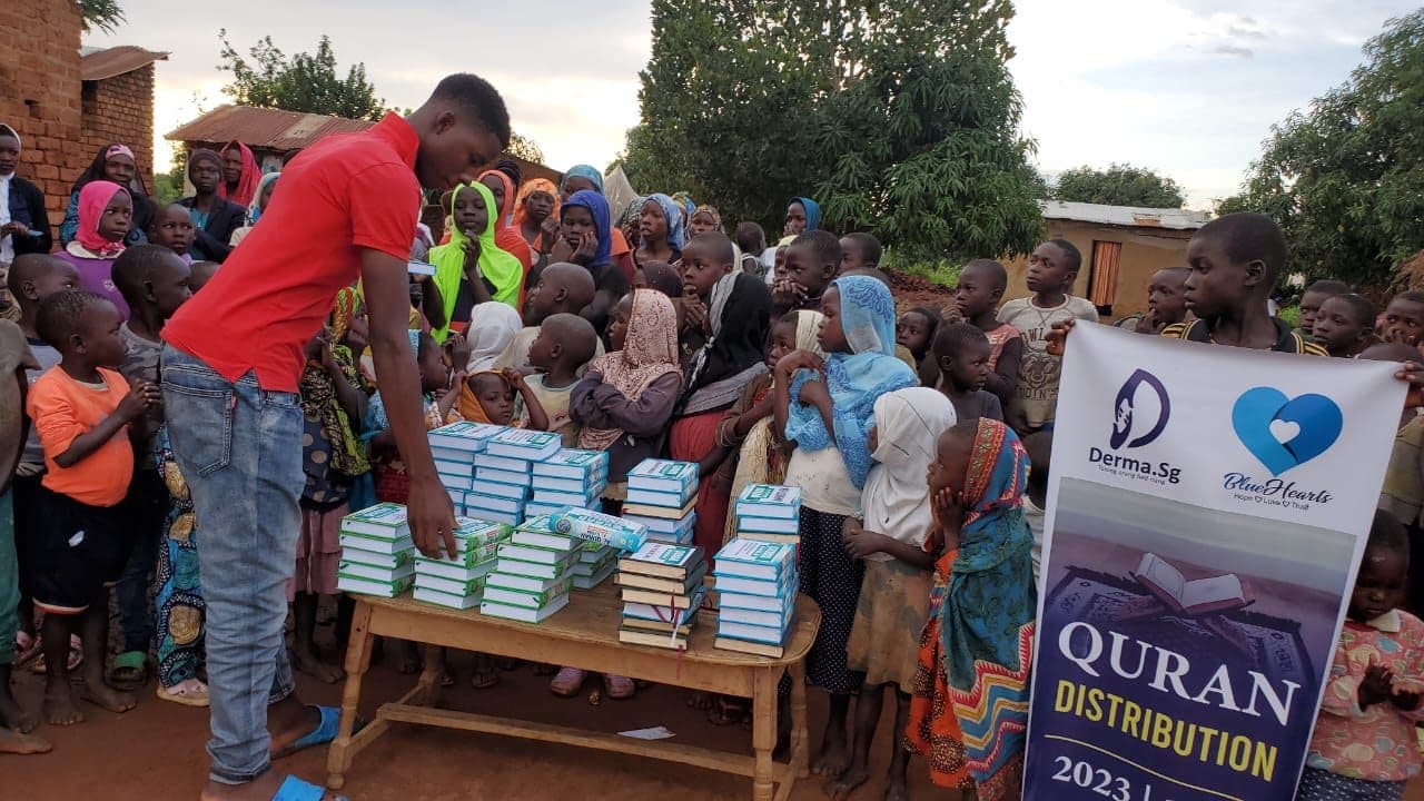 A volunteer handing out Qurans at a Derma SG distribution