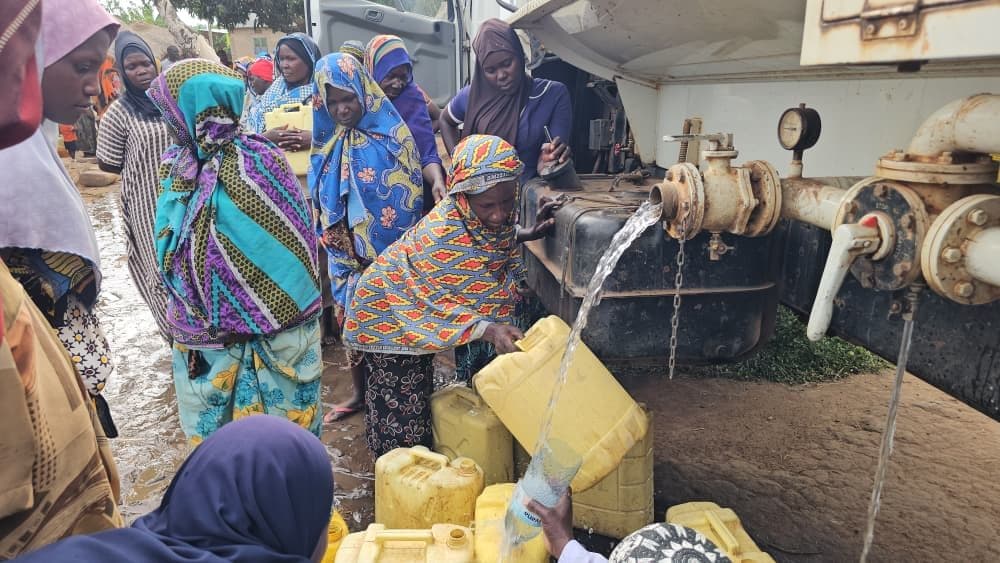 Families filling jerrycans at a Derma SG water distribution in Sudan